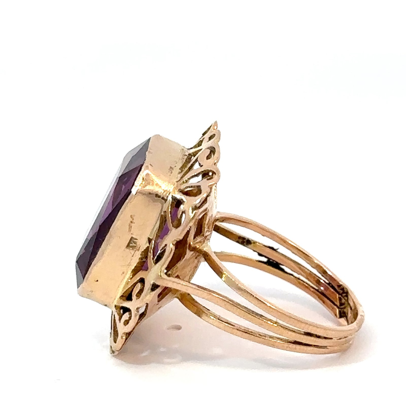 Angled side shot of an 18k yellow gold amethyst ring from John's Loan & Jewelry, highlighting the intricate openwork design and the rich purple of the birthstone jewelry.