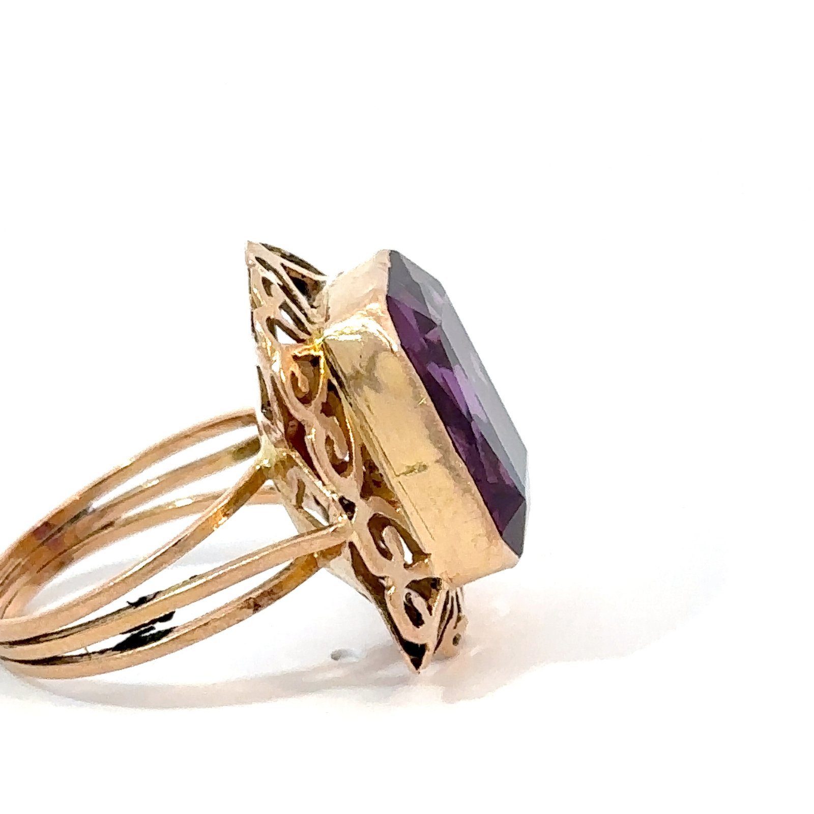 Side-profile view of an 18k yellow gold amethyst ring from John's Loan & Jewelry, showcasing the stone's depth and the ring's multi-band design and ornate gold setting.