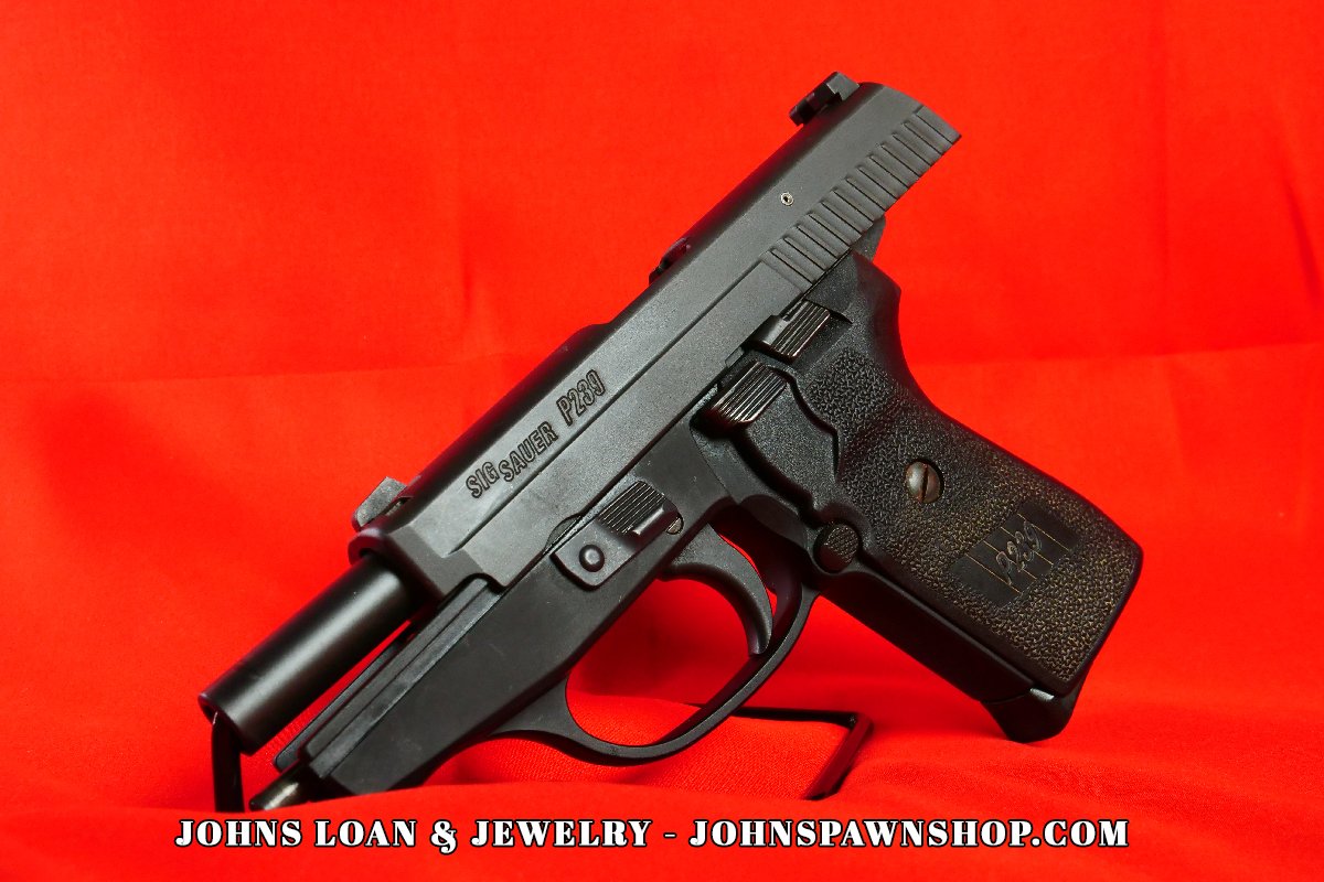 Angled image of a Sig Sauer P239 9mm semi auto pistol on a stand, showing the slide and textured grip at John's Loan & Jewelry, a trusted pawn shop.