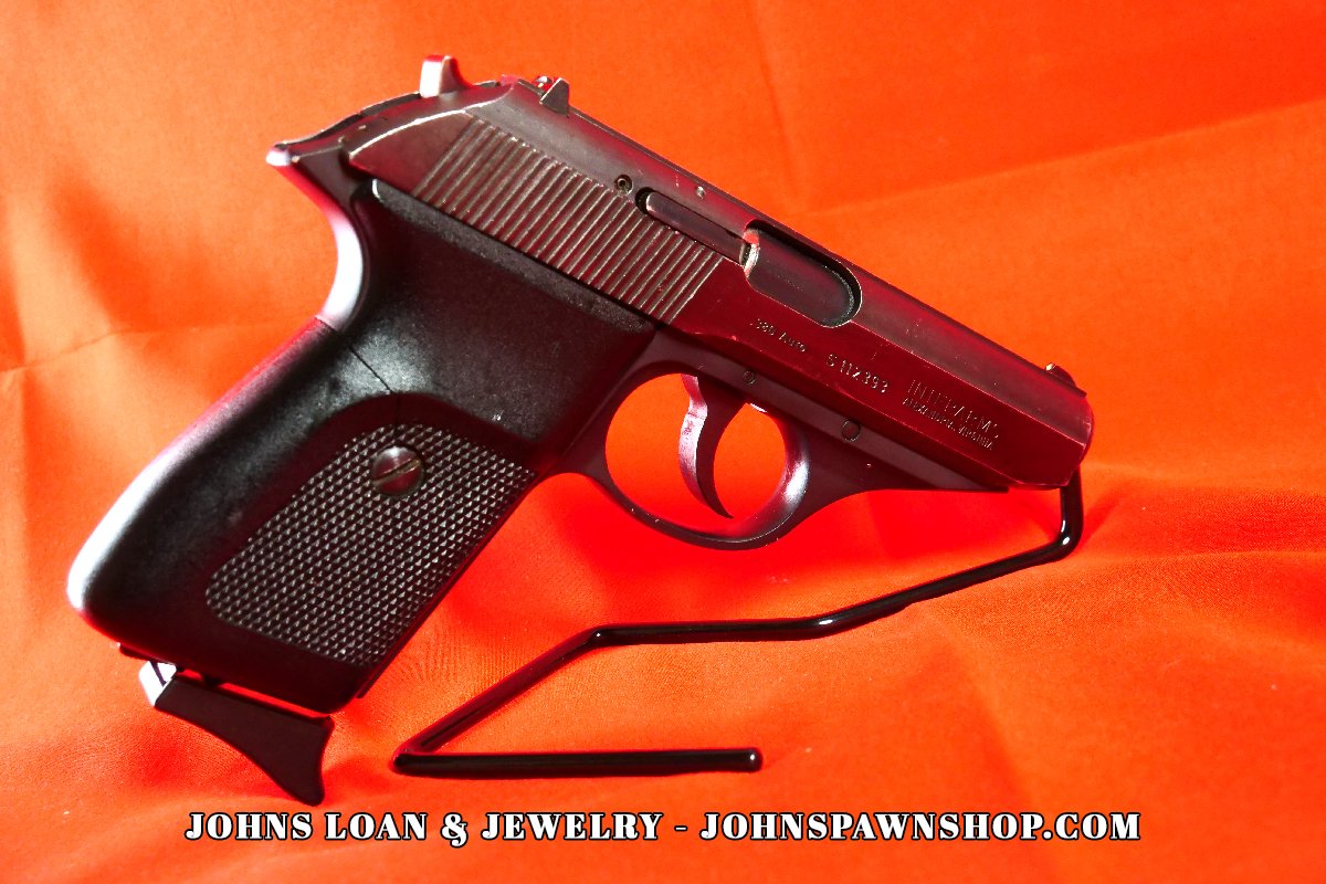 Angled view of the Sig Sauer P230 .380 ACP pistol, featuring a blued steel slide and black polymer frame, displayed by John's Loan & Jewelry as a compact firearm.