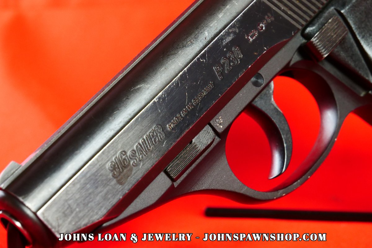 Detailed shot of the Sig Sauer P230 pistol, highlighting the "Sig Sauer" engraving and DA/SA trigger, presented by John's Loan & Jewelry as a perfect CCW firearm.