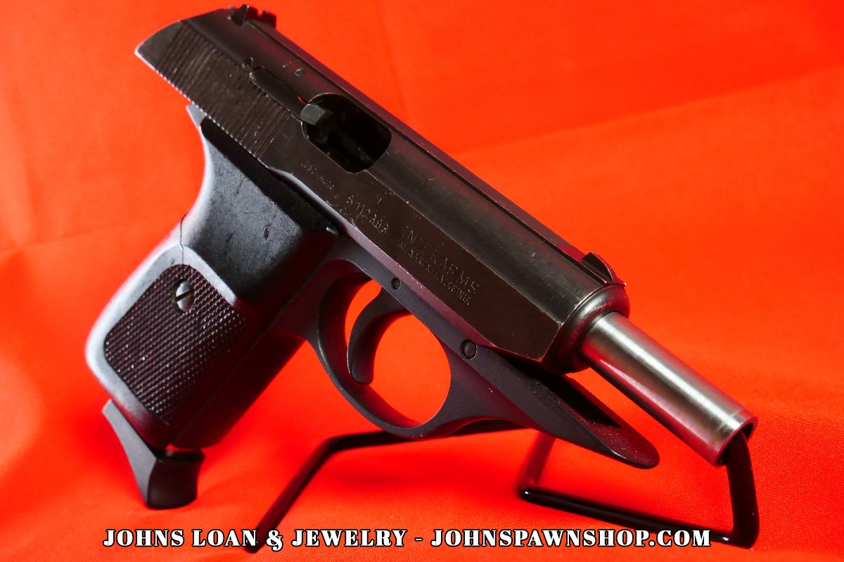 Side profile of a Sig Sauer P230 .380 ACP pistol, featuring a blued steel slide and black polymer frame, displayed by John's Loan & Jewelry as a classic concealed carry firearm.