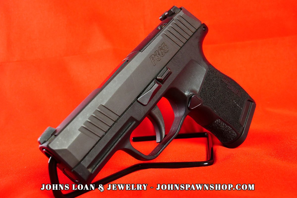 Angled shot of a Sig Sauer P365 pistol, highlighting the slide, frame, and textured grip, offered for sale by John's Loan & Jewelry.