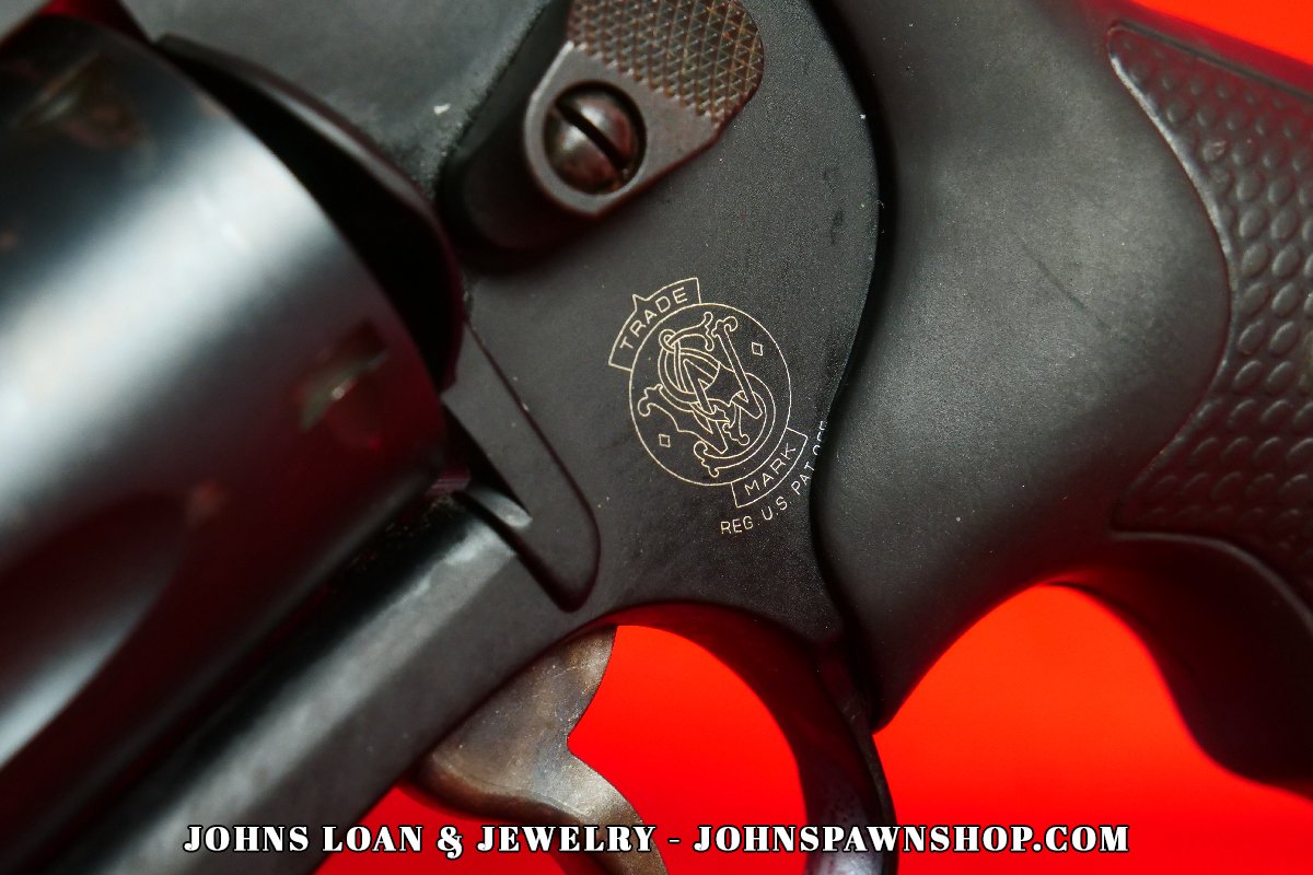 Macro shot of the Smith & Wesson emblem on the 442-1 J Frame revolver, showing fine details of the frame and textured grip, available at John's Loan & Jewelry for .38 Special firearm enthusiasts.