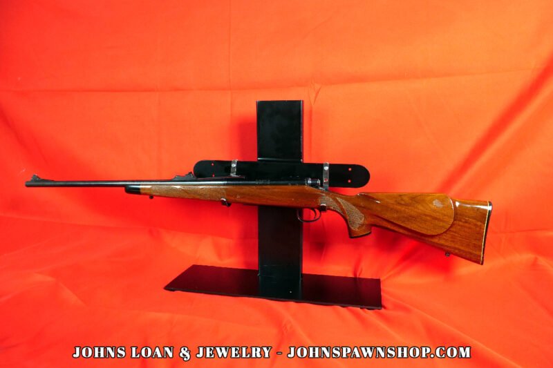Remington Model 700 bolt action hunting rifle in .30-06, featuring a glossy wood stock and blued steel barrel, presented by John's Loan & Jewelry.