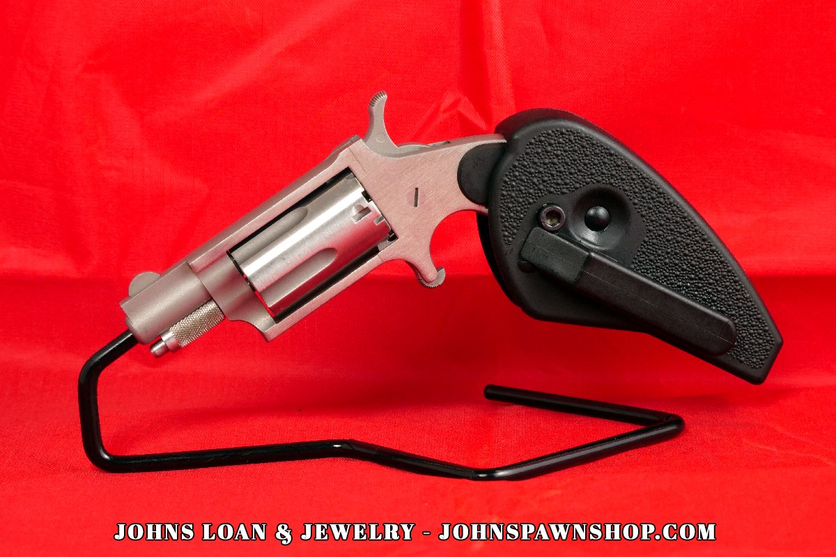 Side profile of the North American Arms .22 Magnum revolver from John's Loan & Jewelry, highlighting its compact design, stainless finish, holster grip, and the firearm's overall near perfect shape.