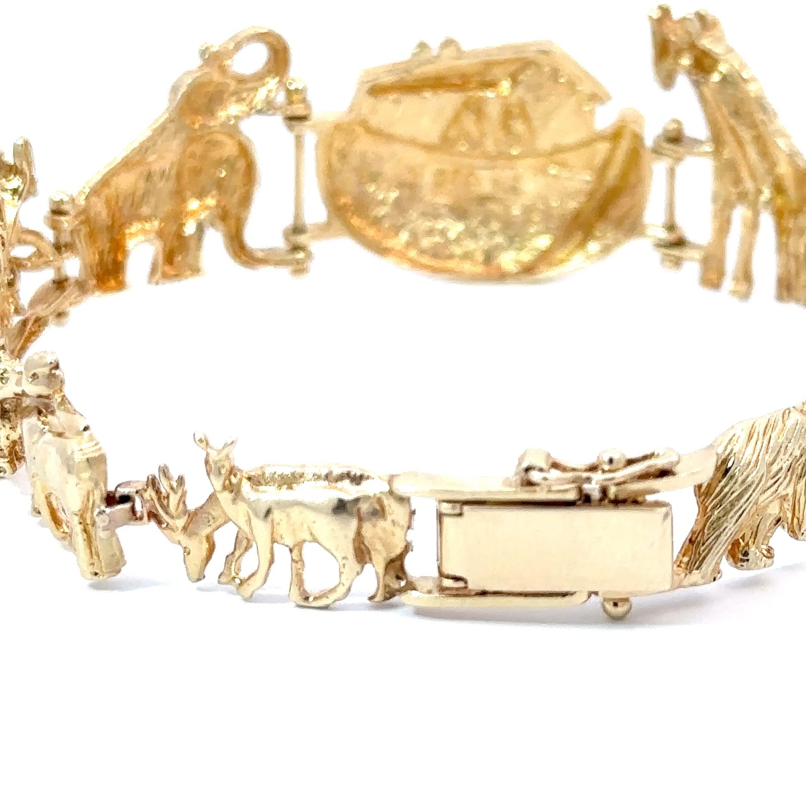 The 14k gold Noah's Ark bracelet from John's Loan & Jewelry showcases a full animal charm panorama, including deer and other motifs. The jewelry piece is displayed on a white table.