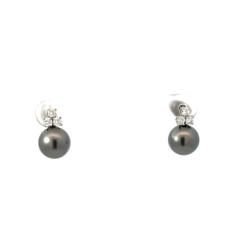 Two 14kt white gold earrings from John's Loan & Jewelry featuring round, black pearls with a trio of prong-set diamonds above, displayed on a white table.