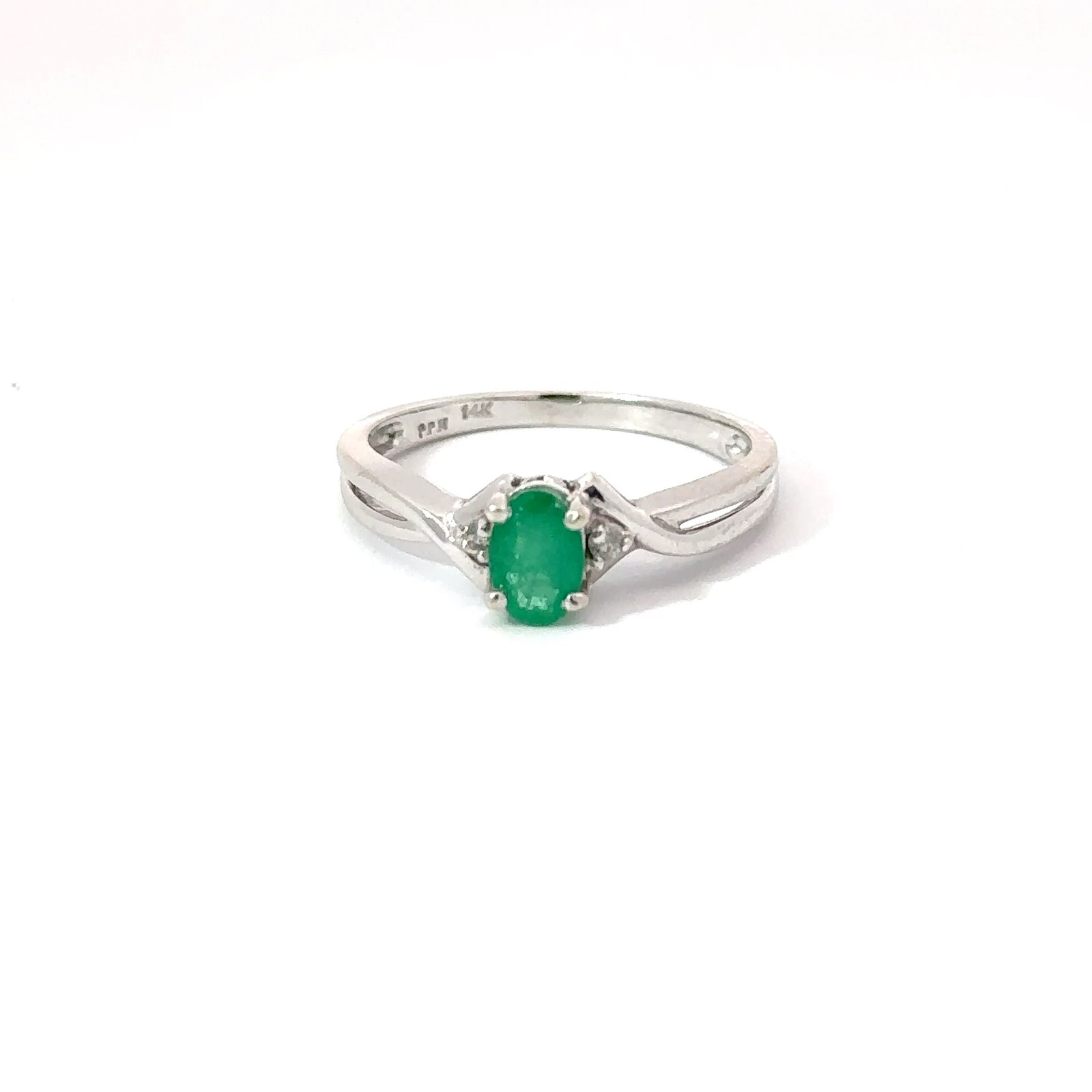 Oval-cut 0.3ct emerald solitaire ring in polished 14k white gold setting from John's Loan & Jewelry; detail shows split shank and subtle diamond accents.
