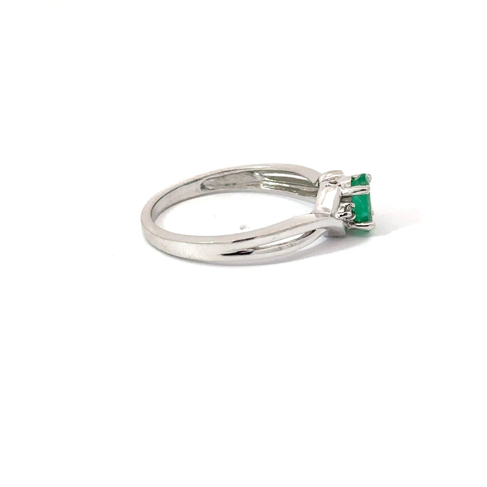 Angled side view of a 14k white gold emerald solitaire ring from John's Loan & Jewelry focusing on the .3ct emerald cut and polished precious metal band.