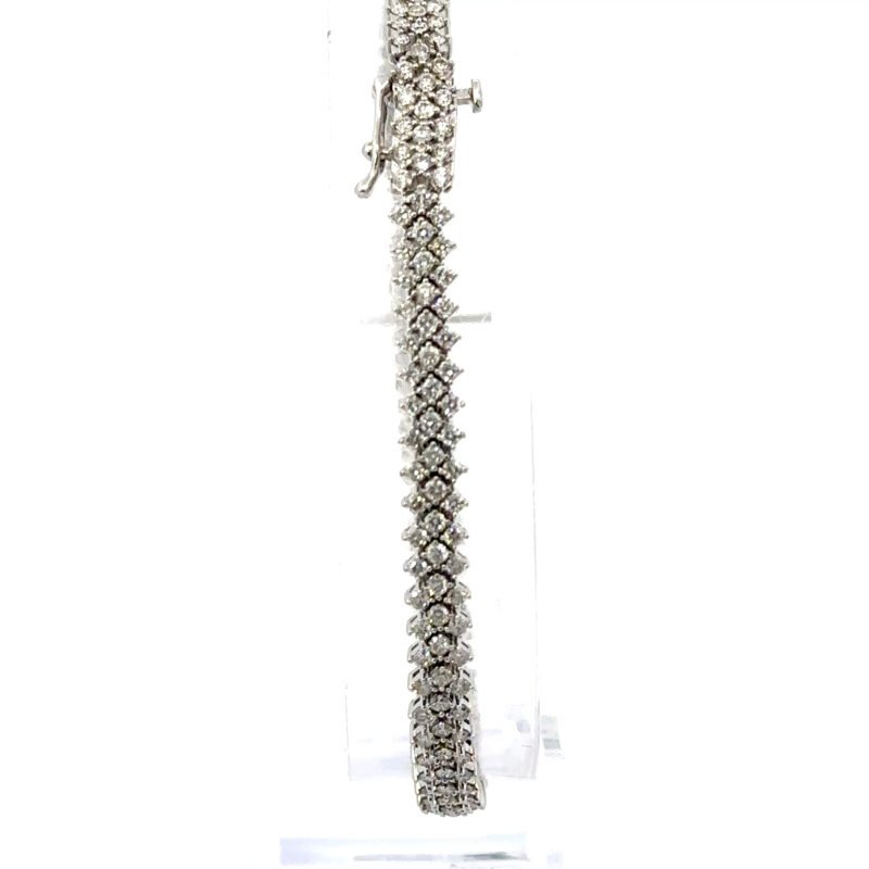 Close-up image of a 10K white gold bracelet from John's Loan & Jewelry, featuring three parallel rows of prong-set diamonds against a stark white background.
