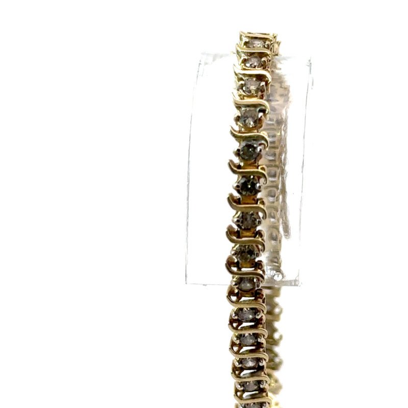 Close-up image of a John's Loan & Jewelry 10k yellow gold tennis bracelet featuring individually set, natural diamonds, displayed vertically against a white table surface.