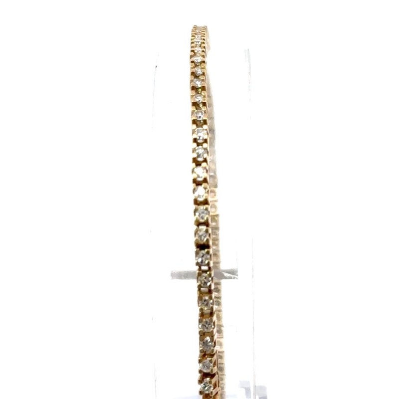 Close up of a 14k gold high-set tennis bracelet featuring round-cut diamonds, displayed on a clear stand; a stacker jewelry piece from John's Loan & Jewelry.