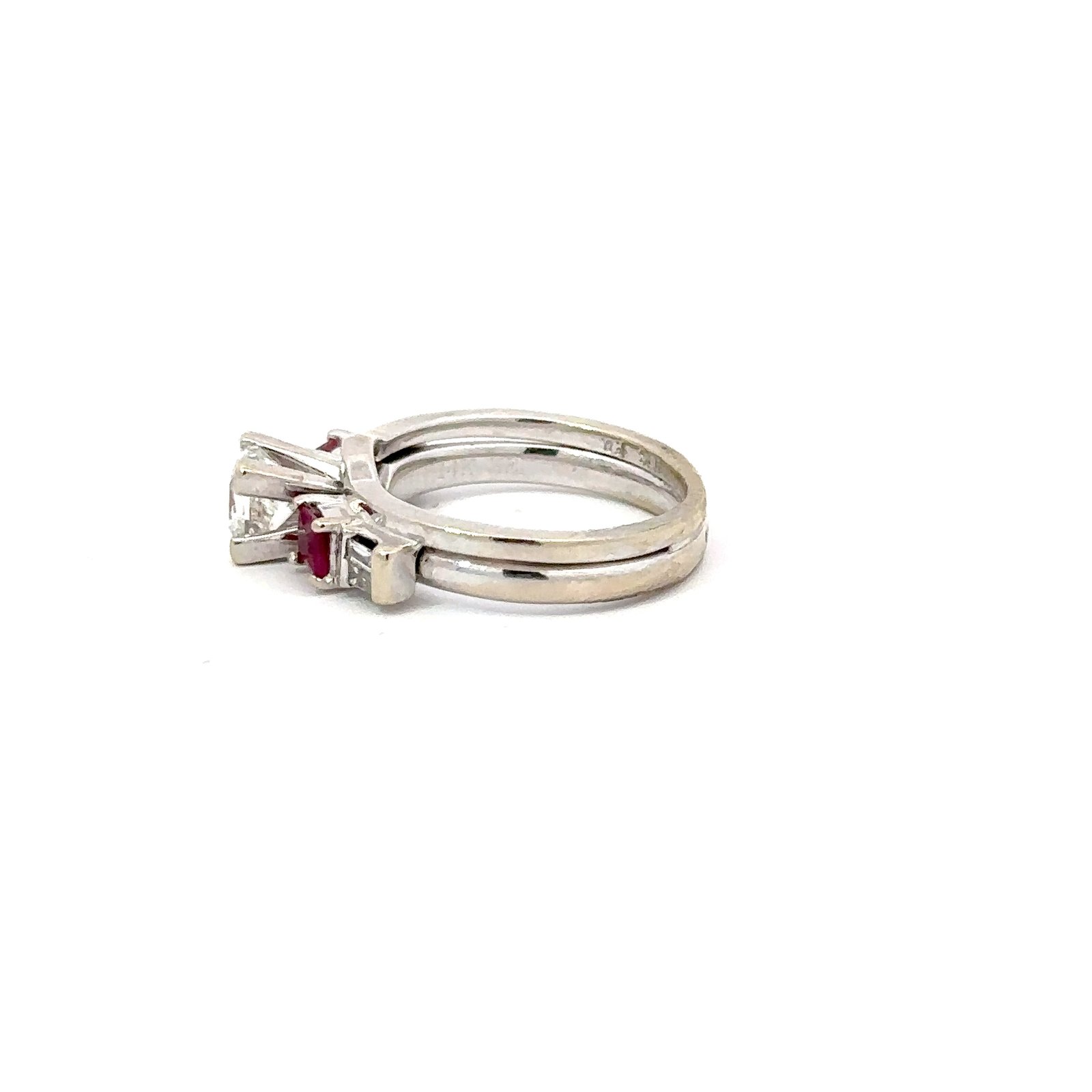 Side view of a 14kt white gold engagement ring from John's Loan & Jewelry, showcasing a princess cut diamond and red ruby accents set along the ring's shank.